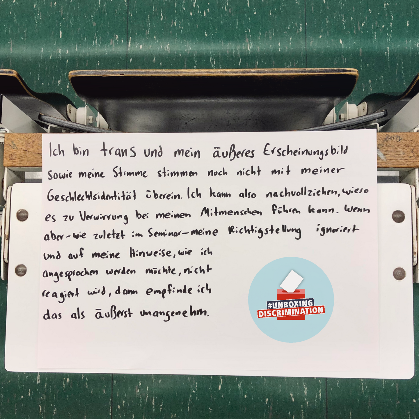  In the lecture hall building, a poster is placed on a folded-out table on which, next to the logo of the #unboxingdiscrimination campaign, the handwritten text: "I am trans and my outward appearance and voice do not yet match my gender identity. So I can understand why confusion can arise among my fellow men. However, if - as recently in a seminar - my correction is ignored and no reaction is made to my instructions on how I would like to be addressed, then I find this extremely unpleasant.