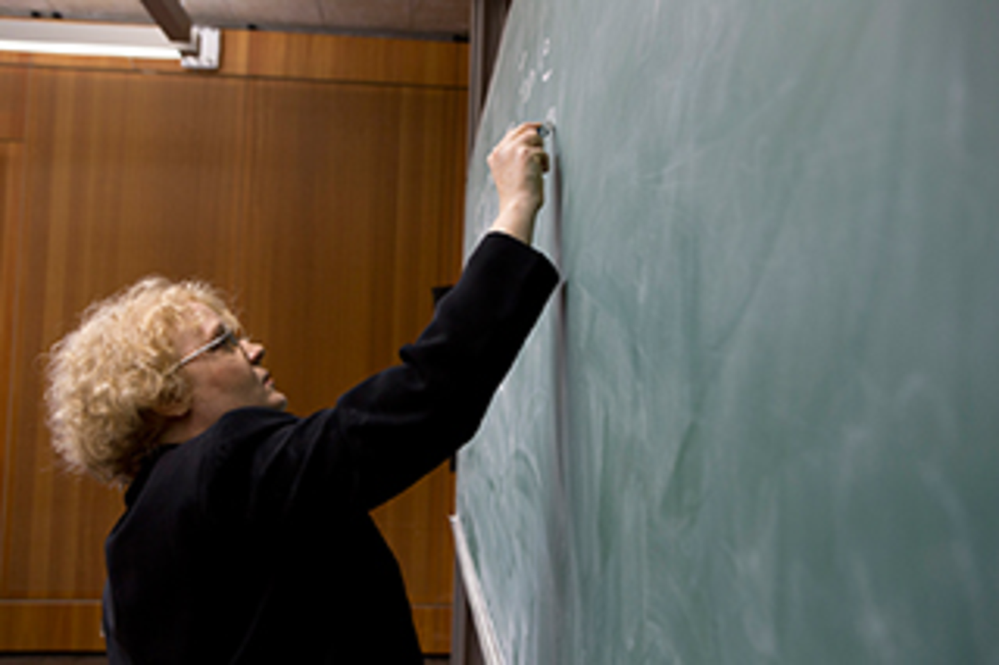 A woman is wiriting on a chalk board.