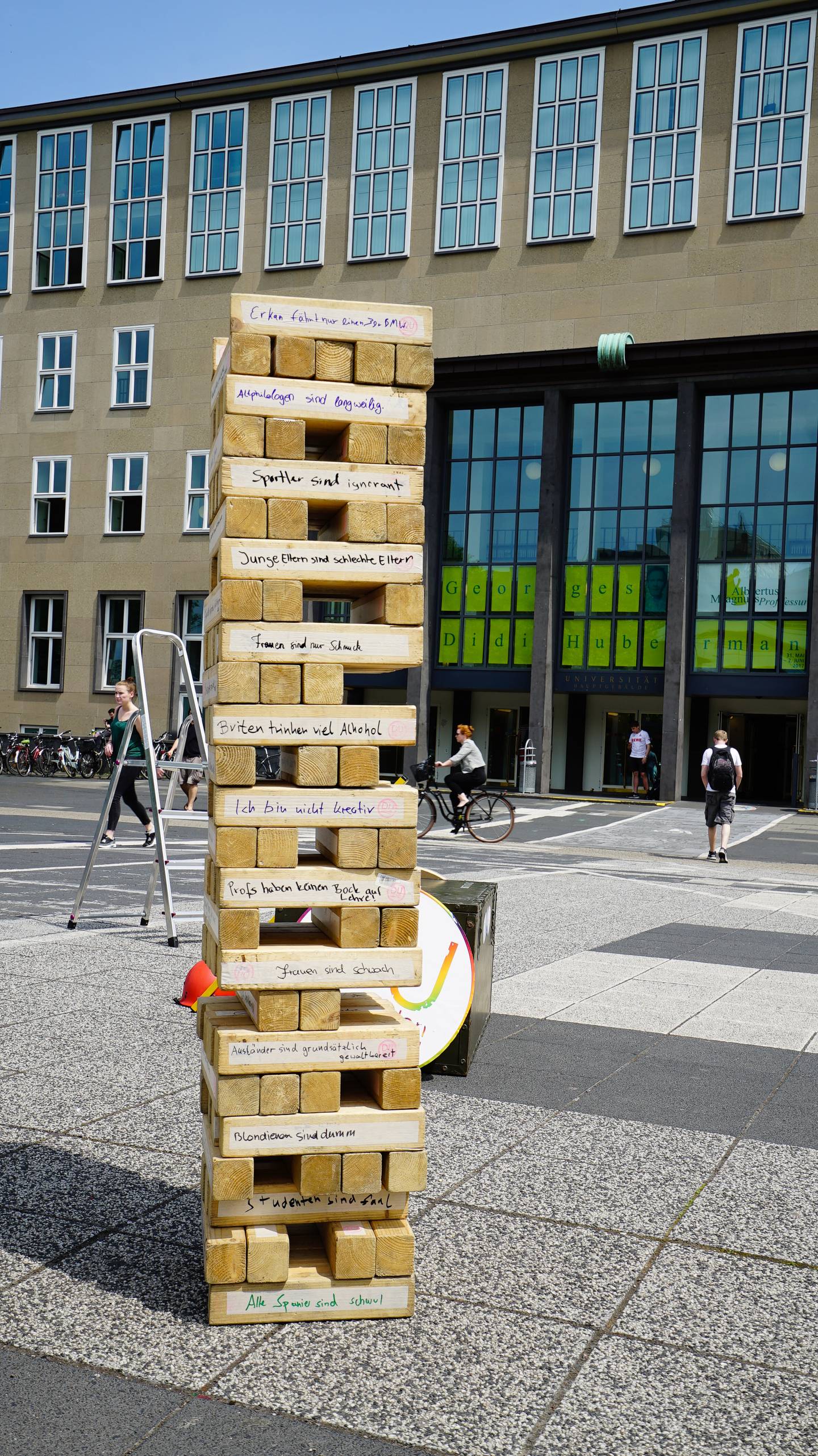 Ein großer Jenga Turm auf dem Albert-Magnus-Platz. Die Steine sind mit Vorurteilen beschriftet.