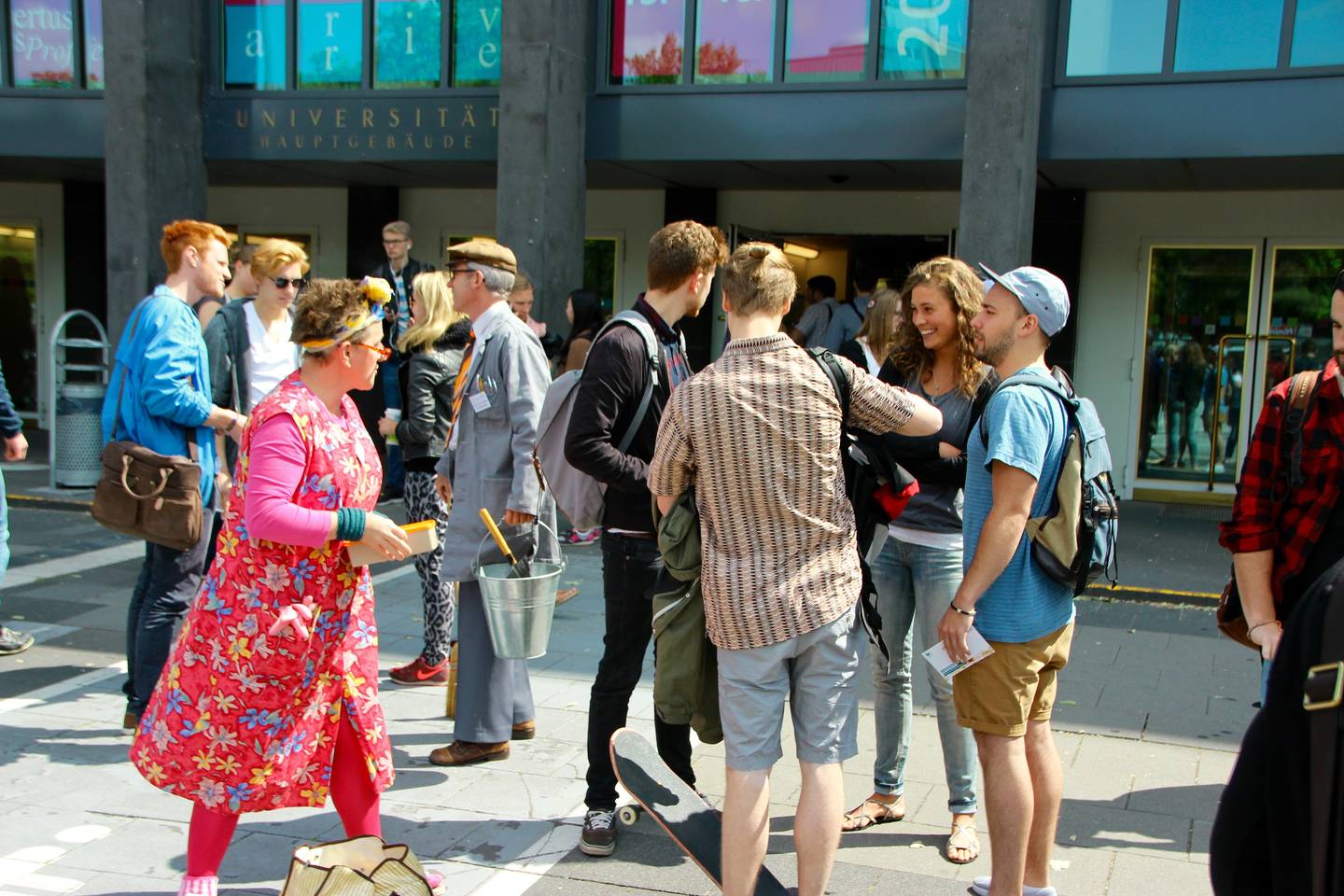 Studierende, die auf dem Albertus Magnus Platz mit den beiden Schauspielenden des Improvisationstheaters im Gespräch sind.