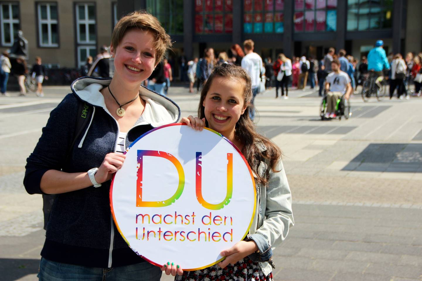 Zwei Studentinnen halten gemeinsam das Logo der Themenwoche "Du machst den Unterschied"